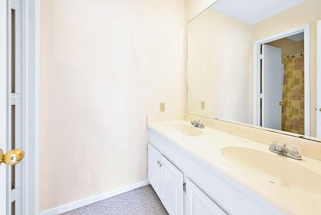 bathroom featuring double vanity, curtained shower, baseboards, and a sink