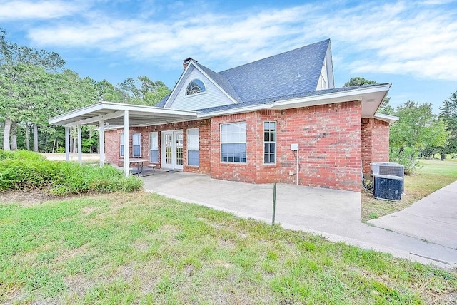 back of property featuring french doors, a lawn, brick siding, and central air condition unit