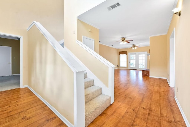 interior space featuring hardwood / wood-style floors, baseboards, visible vents, and crown molding