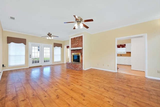 unfurnished living room with crown molding, visible vents, a brick fireplace, light wood-type flooring, and baseboards