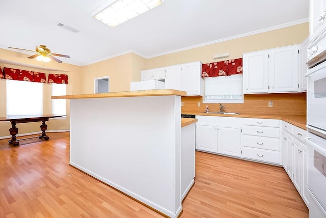 kitchen with white cabinets, light countertops, a sink, and visible vents