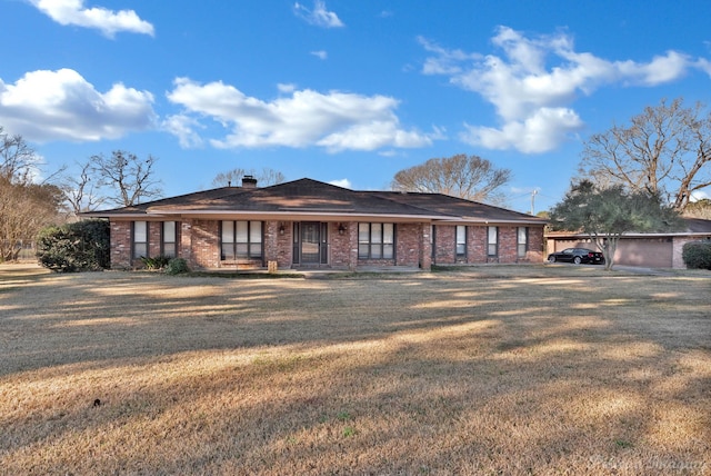 ranch-style house with brick siding, a front lawn, and a chimney