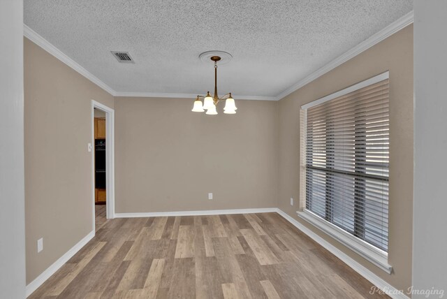 unfurnished room featuring an inviting chandelier, baseboards, visible vents, and wood finished floors