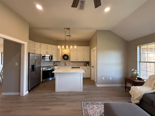 kitchen featuring open floor plan, stainless steel appliances, light countertops, white cabinetry, and backsplash