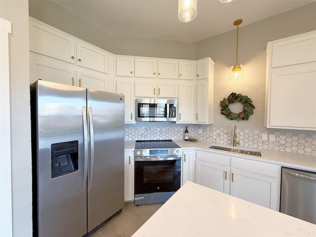 kitchen featuring white cabinets, decorative backsplash, appliances with stainless steel finishes, light countertops, and a sink