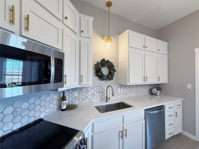 kitchen featuring tasteful backsplash, appliances with stainless steel finishes, light countertops, and a sink