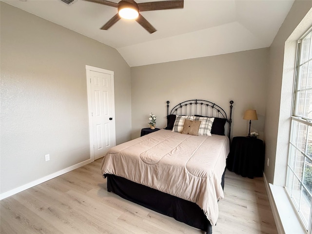 bedroom featuring multiple windows, baseboards, vaulted ceiling, and wood finished floors