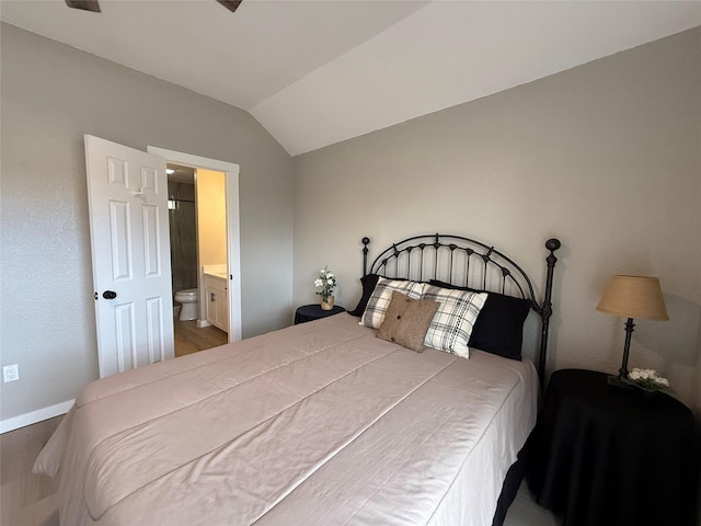 bedroom with vaulted ceiling, baseboards, and ensuite bathroom