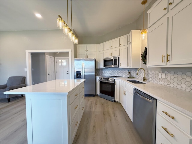 kitchen featuring a sink, appliances with stainless steel finishes, light wood-type flooring, decorative backsplash, and a center island