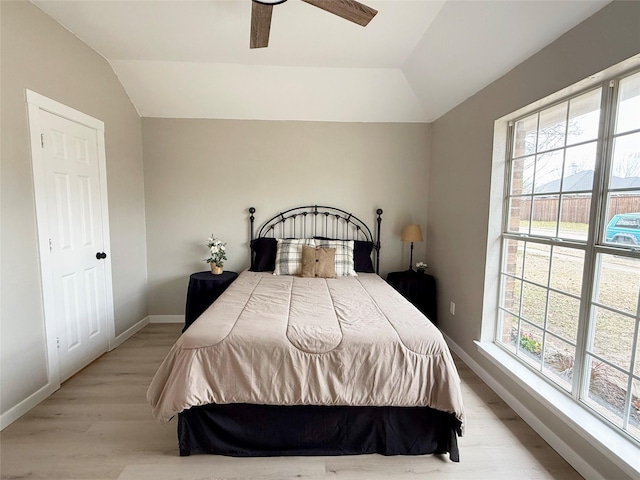 bedroom with lofted ceiling, light wood-style floors, multiple windows, and baseboards