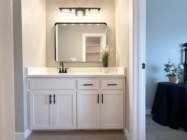 bathroom featuring a textured wall, baseboards, and vanity