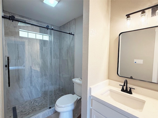 full bathroom with a marble finish shower, a textured wall, vanity, and toilet