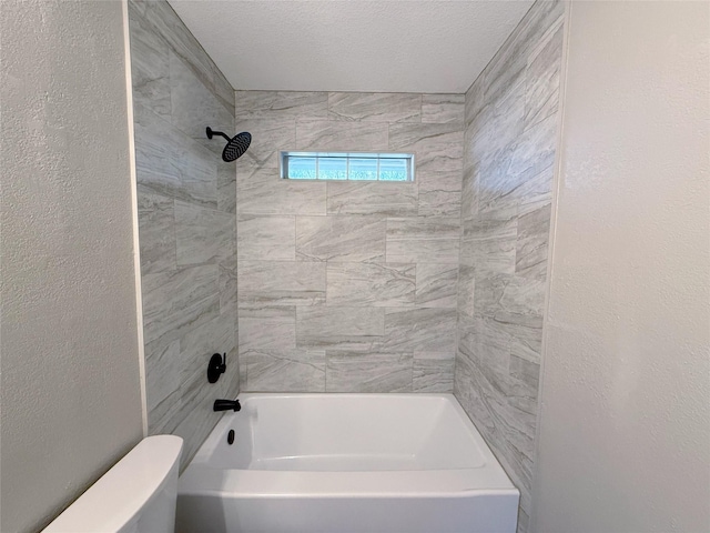 full bathroom with toilet, tub / shower combination, a textured ceiling, and a textured wall