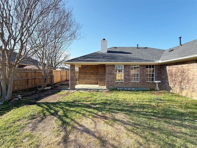 back of property featuring brick siding, a yard, a chimney, a shingled roof, and fence