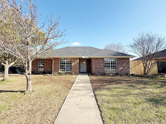 ranch-style home featuring a front yard, brick siding, and roof with shingles