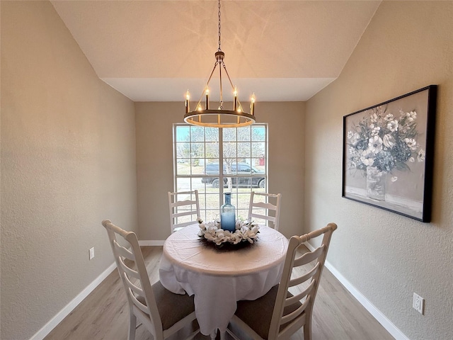 dining space with an inviting chandelier, baseboards, wood finished floors, and a textured wall