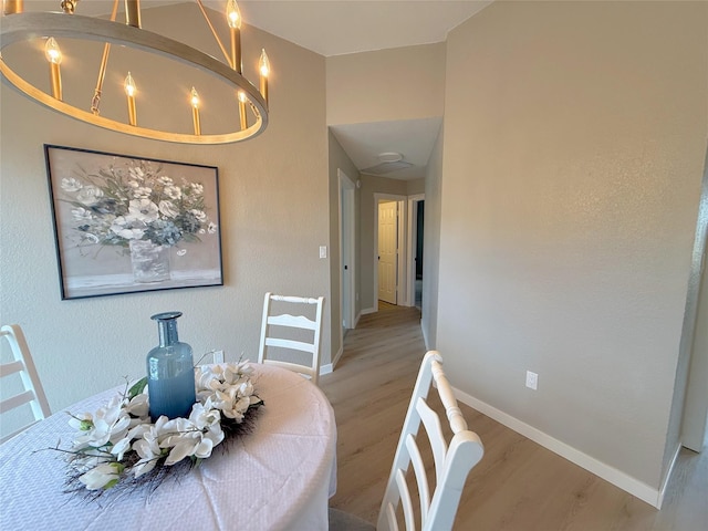 dining room with light wood-style floors, a notable chandelier, and baseboards