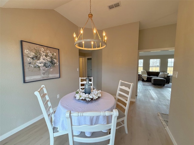 dining area featuring a chandelier, visible vents, baseboards, vaulted ceiling, and light wood-style floors