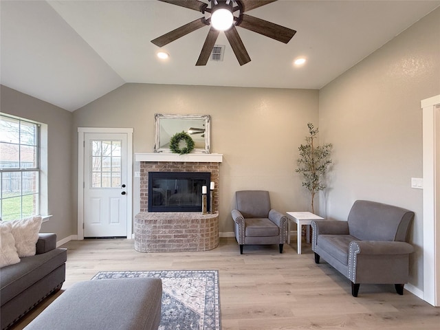 living room with light wood-type flooring, lofted ceiling, visible vents, and baseboards