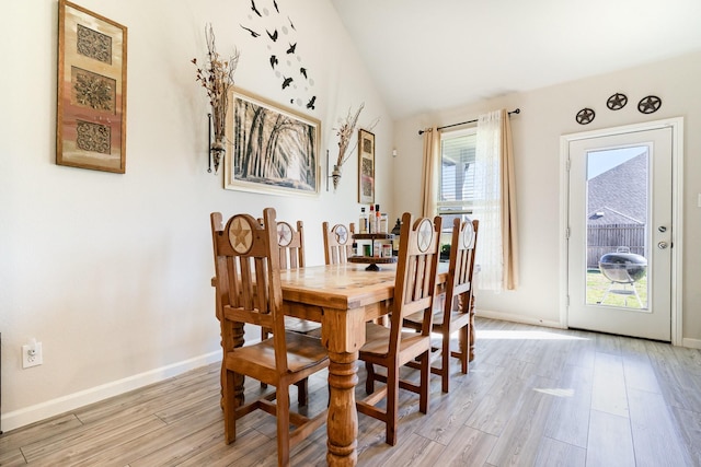 dining room with lofted ceiling, baseboards, and light wood-style floors