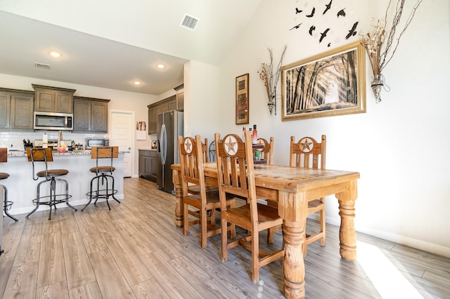 dining space with lofted ceiling, light wood-type flooring, visible vents, and recessed lighting