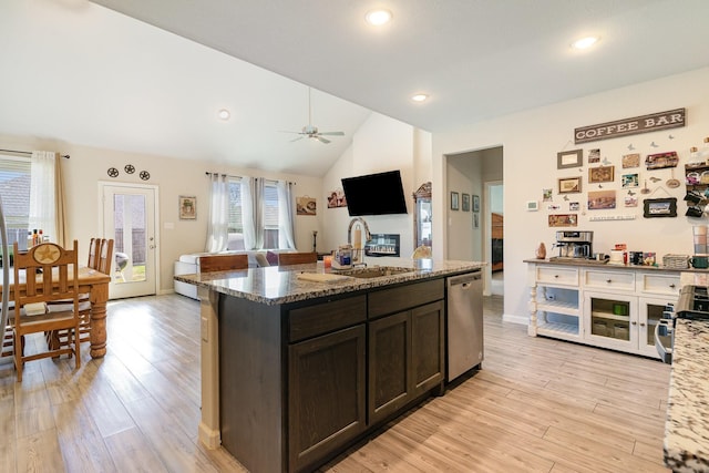 kitchen featuring light wood-style floors, vaulted ceiling, dark brown cabinets, appliances with stainless steel finishes, and light stone countertops