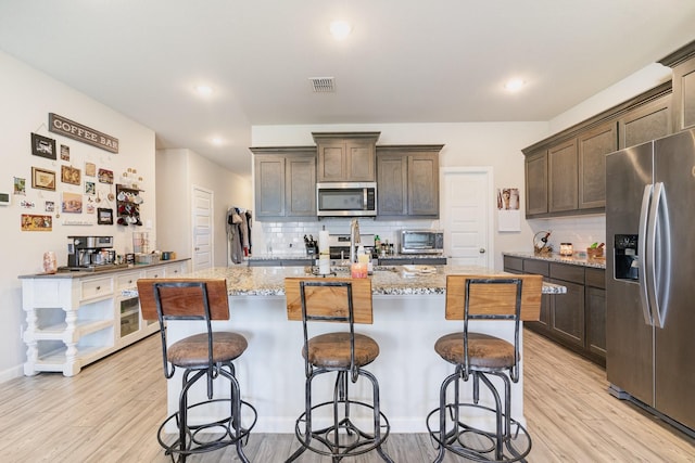 kitchen with appliances with stainless steel finishes, visible vents, dark brown cabinetry, and light wood-style flooring