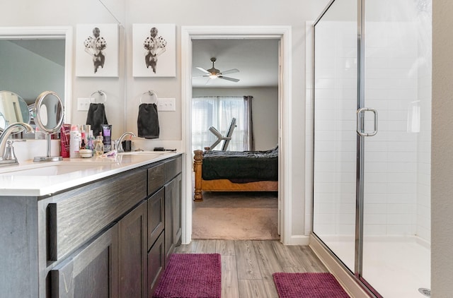 full bathroom with a shower stall, connected bathroom, a sink, and wood finished floors