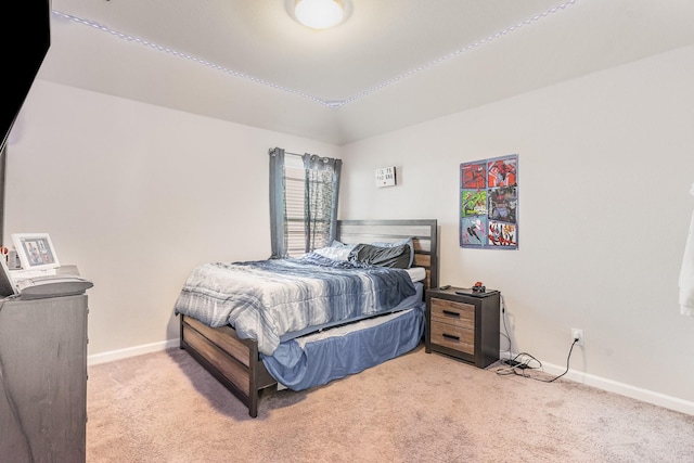 carpeted bedroom with lofted ceiling and baseboards