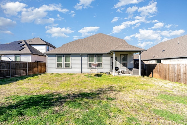 rear view of house featuring a shingled roof, a patio area, a fenced backyard, and a yard