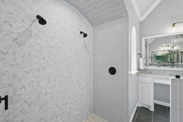 full bath with vaulted ceiling, tiled shower, vanity, and tile patterned floors