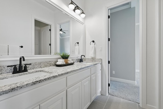 bathroom with double vanity, baseboards, a sink, and tile patterned floors