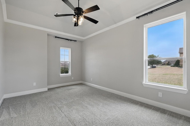 carpeted empty room with ceiling fan, baseboards, and crown molding