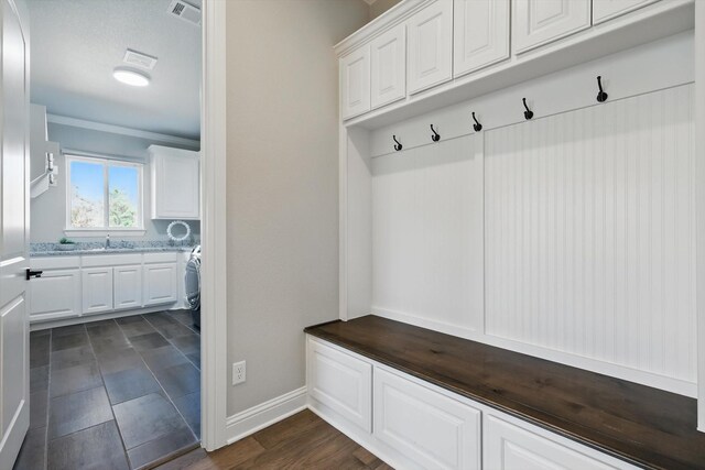 mudroom with dark wood-style floors, baseboards, visible vents, and a sink