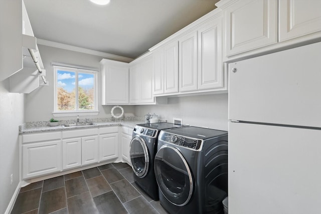 laundry area with washing machine and clothes dryer, a sink, cabinet space, and baseboards