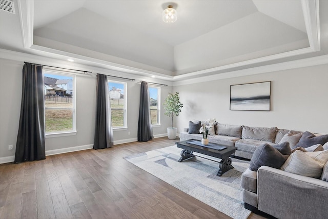 living room featuring visible vents, baseboards, a raised ceiling, and wood finished floors