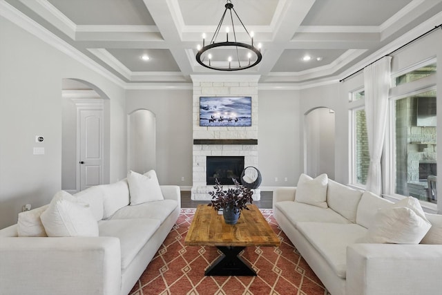 living area with baseboards, coffered ceiling, beam ceiling, and a stone fireplace