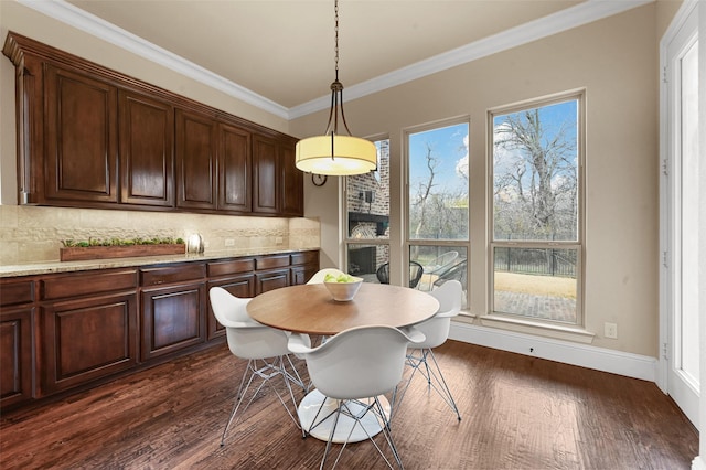 dining space featuring dark wood-type flooring, ornamental molding, and baseboards