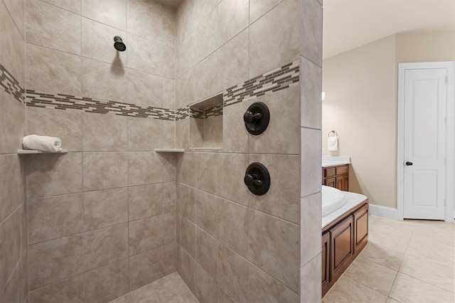 bathroom featuring a tile shower, vanity, and baseboards