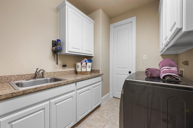 kitchen with washer / dryer, light tile patterned floors, light countertops, white cabinetry, and a sink