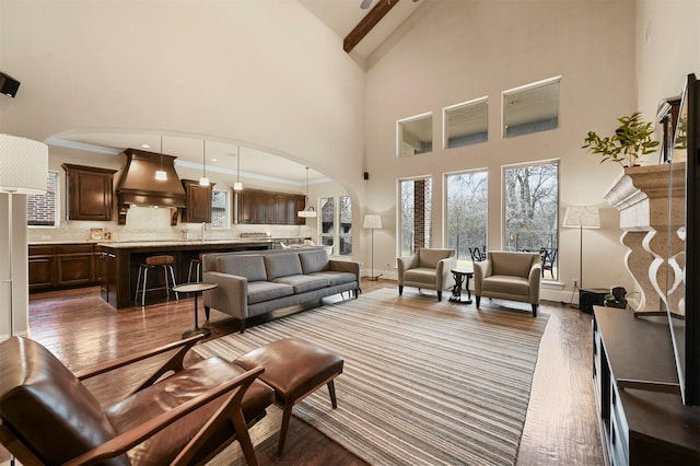 living area with dark wood-style floors, arched walkways, and high vaulted ceiling