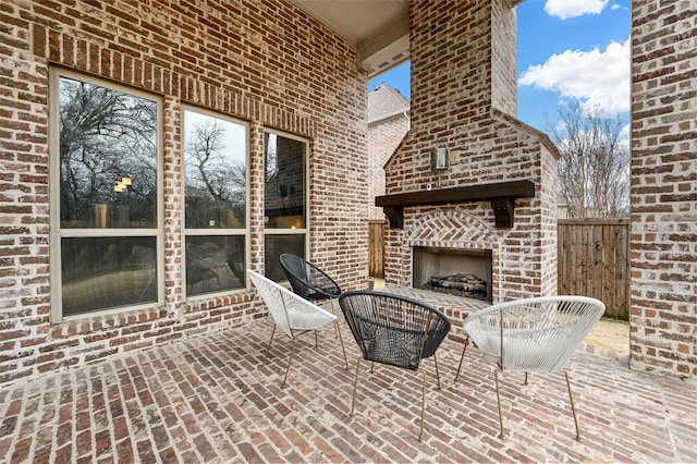 view of patio featuring an outdoor brick fireplace and fence