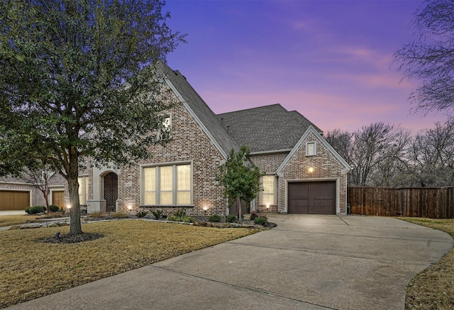 view of front of property with brick siding, a yard, fence, a garage, and driveway