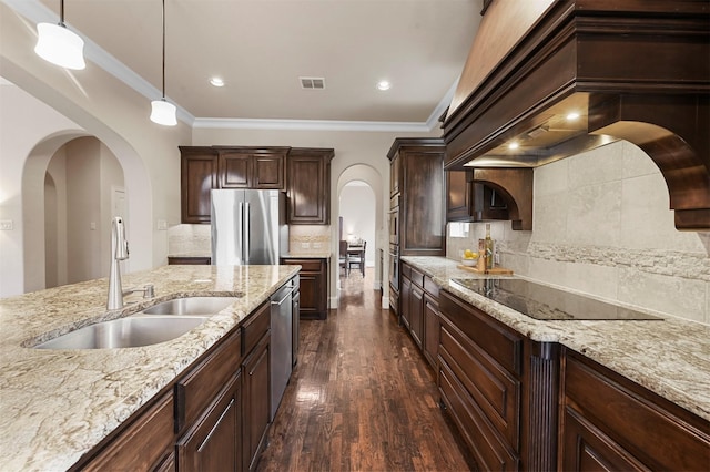 kitchen featuring arched walkways, dark wood-type flooring, a sink, visible vents, and appliances with stainless steel finishes