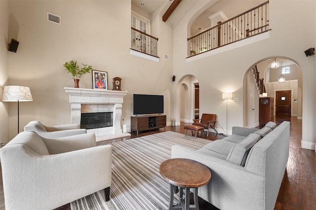 living area featuring dark wood-style floors, arched walkways, visible vents, a high end fireplace, and baseboards