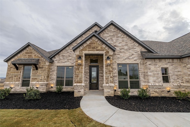 french country style house featuring brick siding and roof with shingles