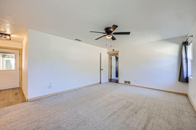 carpeted spare room featuring visible vents, ceiling fan, a textured ceiling, and baseboards