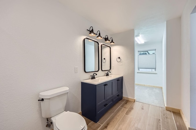 bathroom featuring wood finish floors, baseboards, a sink, and toilet