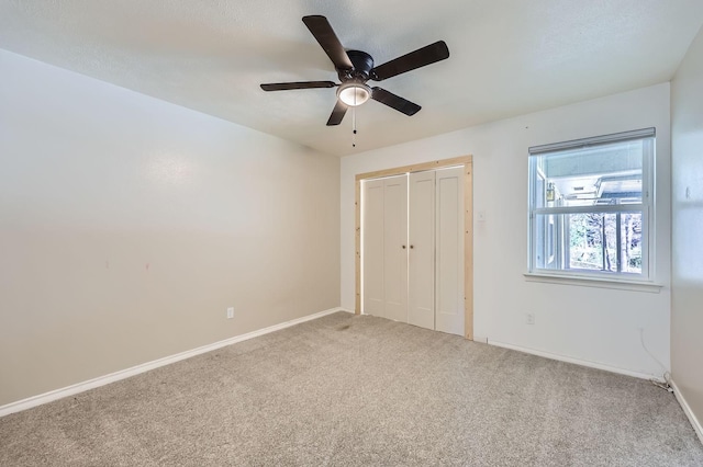 unfurnished bedroom featuring a ceiling fan, a closet, carpet flooring, and baseboards