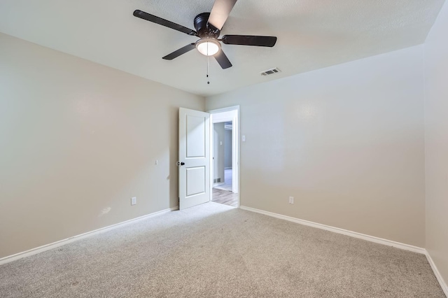 empty room with a ceiling fan, visible vents, light carpet, and baseboards